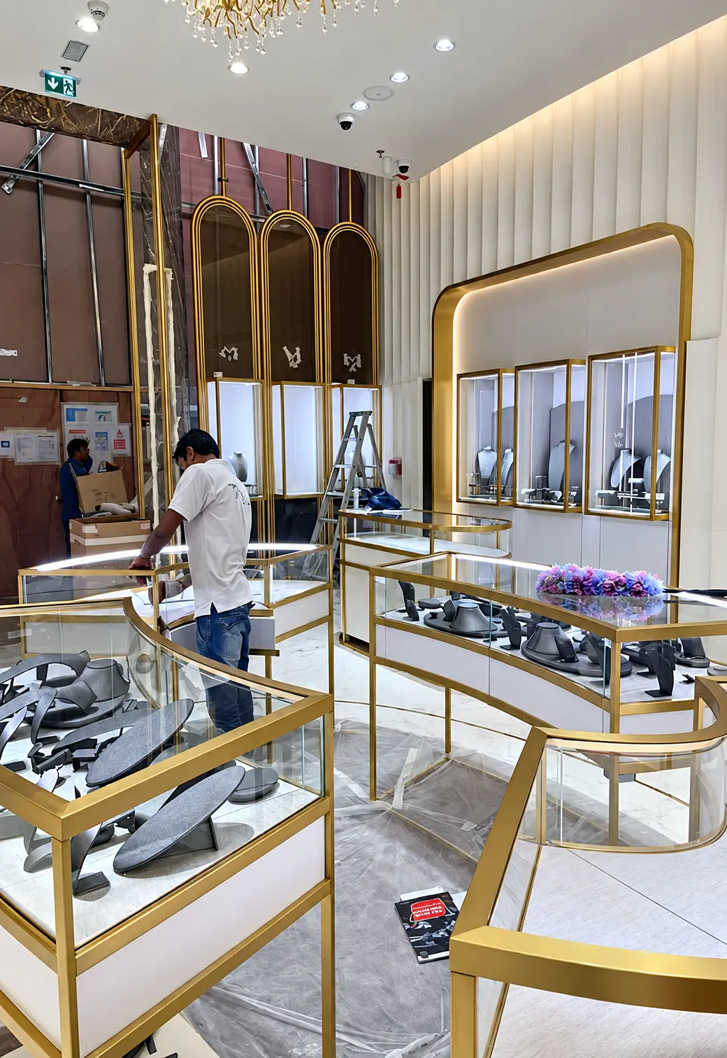 Gold-toned metal retail display cases and wall surrounds during installation