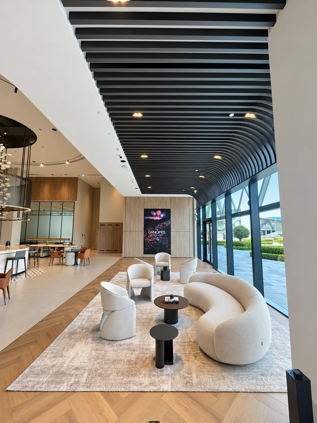 Curved black metal slatted ceiling feature beside a glazed wall